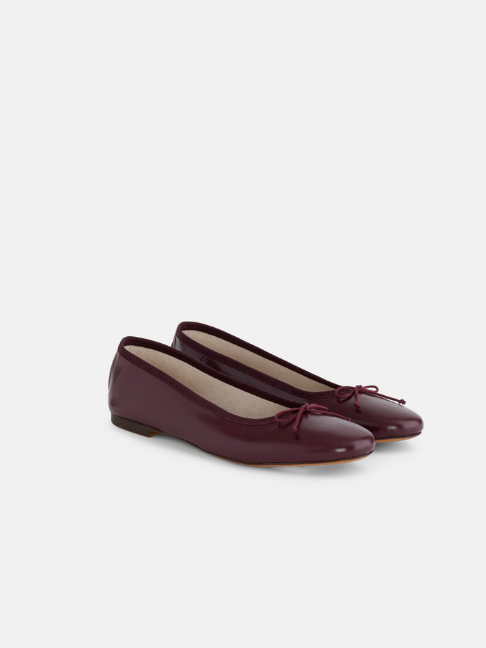 A pair of Prince Street Ballet Flats in shiny burgundy leather, featuring small bows on the toes, are positioned side by side on a plain white background.