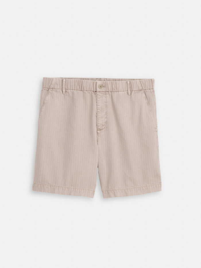 The Pull On Short In Cotton Herringbone features a beige pigment-dyed finish with side pockets, displayed against a plain white background.
