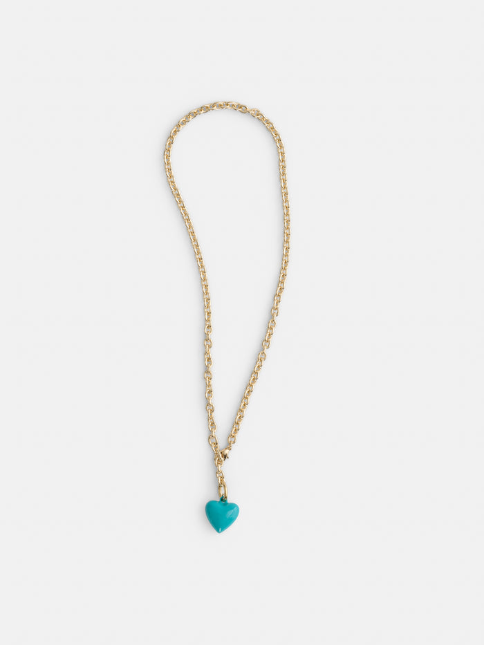 The Roxanne Assoulin Mini Puffy Heart Necklace showcases a turquoise heart-shaped pendant on a gold brass cable chain, set against a plain white background.