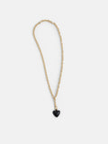The Roxanne Assoulin Mini Puffy Heart Necklace features a gold puffy heart and a small black heart-shaped pendant on a brass cable chain, shown against a plain white background.