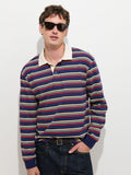 A man stands against a plain white background with one hand in his jeans pocket, looking relaxed, while wearing dark sunglasses and the Rugby Striped in Cotton Jersey—a men’s designer shirt with a boxier fit.