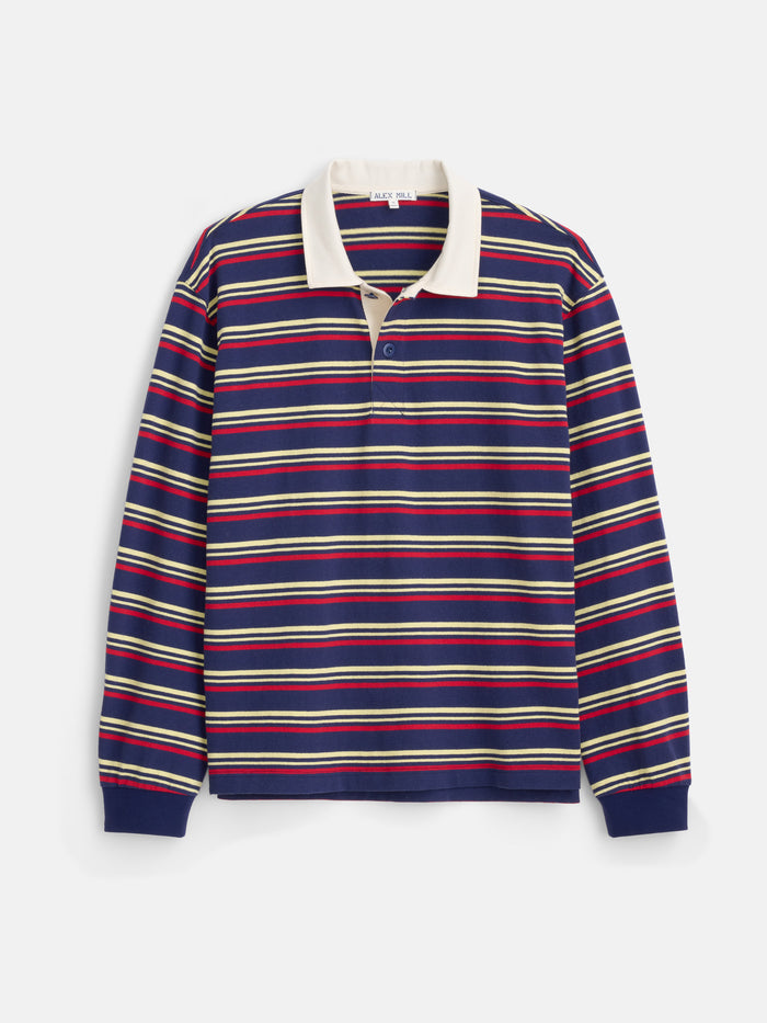 Introducing the Rugby Striped in Cotton Jersey: a men’s designer rugby shirt crafted from herringbone cotton jersey, showcasing horizontal red, yellow, and white stripes over a navy blue base. Featuring a classic white collar and buttoned placket, this long-sleeve shirt is tailored in a boxier fit for a modern yet timeless style.