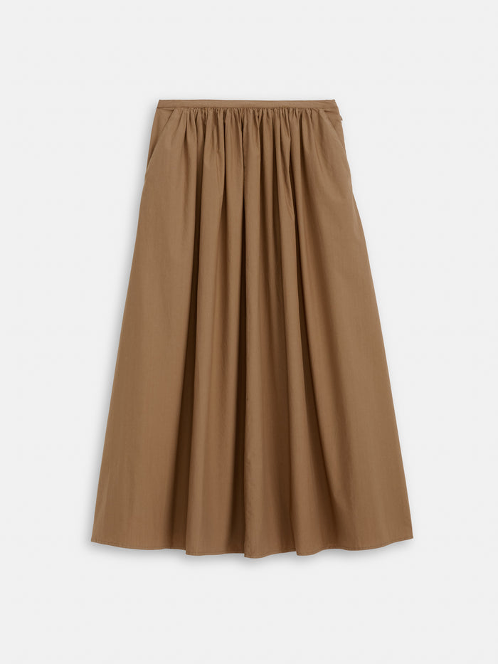 The Sarah Skirt In Cotton is a brown, ankle-length A-line with a gathered stretchy waistband. Made from 100% lightweight cotton, it drapes softly and flows beautifully. Shown against a plain white background.