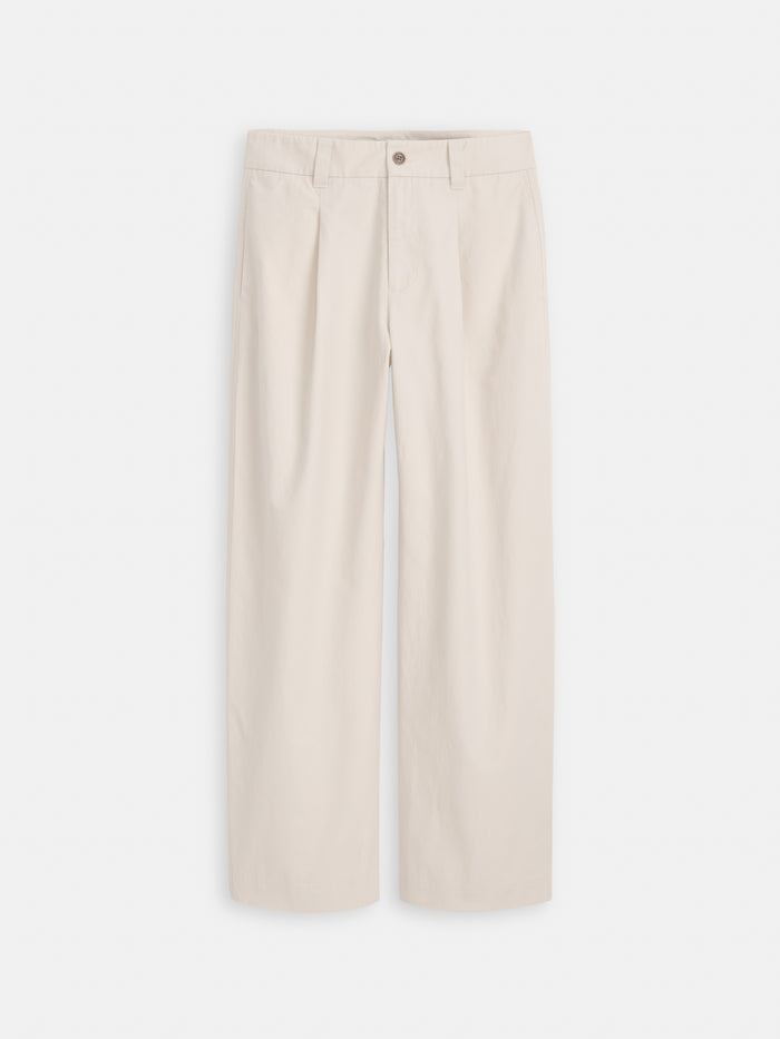 The Soho Pleated Pant In Cotton Linen is a high-waisted, wide-leg cream twill pant with pleats, belt loops, and a button closure, shown on a white background.