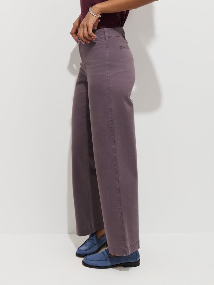 Person wearing the Sutton Pant in Vintage Twill—wide-legged, high-rise chino pants—in purple, paired with blue loafers, standing sideways against a white background. Only the lower half of the body is visible.