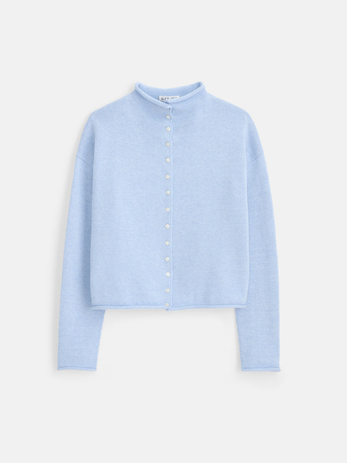 The Taylor Cardigan in Cotton Cashmere is a light blue, long-sleeve sweater with a mock neck and Troca shell buttons down the front. It features an oversized boxy fit and is displayed on a plain white background.