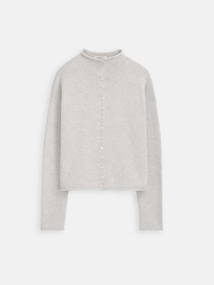 The Taylor Cardigan In Cotton Cashmere features a light gray hue, long sleeves, ribbed knit texture, round neckline, and small front buttons. Hand-finished details are showcased against a plain white background.
