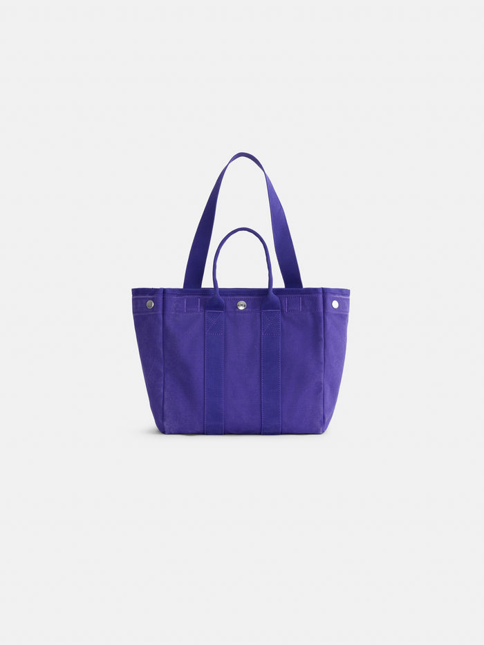 The Perfect Daily Tote, crafted from bright purple cotton, features two short handles and a snap closure, displayed against a plain white background.