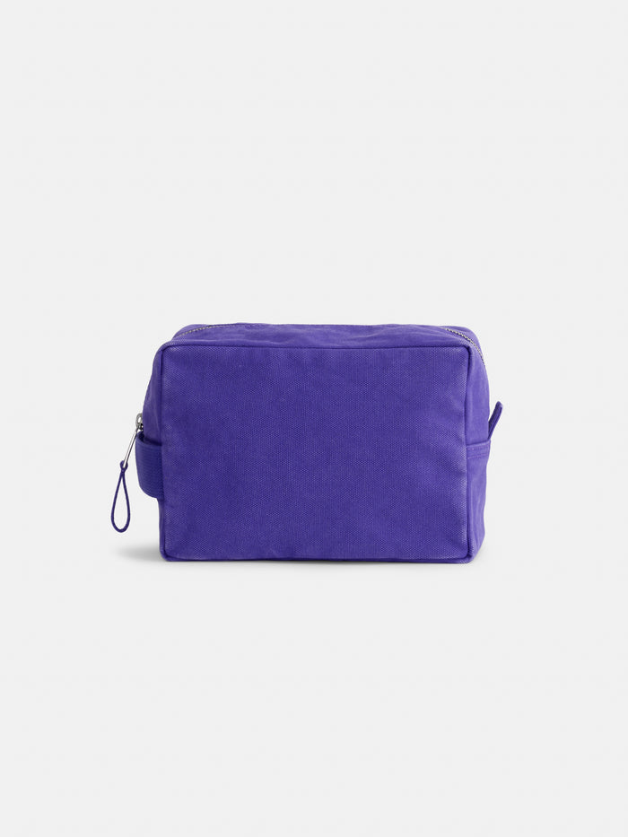 The Painted Perfect Dopp Kit—a rectangular purple zippered canvas pouch with a small side handle— is displayed against a plain white background and is perfect as a makeup bag or personalized toiletry bag for everyday essentials.