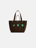 The Painted Perfect Weekday Tote is a brown cotton bag with dark handles and the green initials “JMW” embroidered on the front. This personalized tote features a structured silhouette and silver snap accents near the top edge.