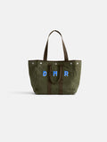 The Perfect Weekday Tote is a green suede bag with brown handles, featuring large blue and white "DMR" letters monogrammed on the front, displayed against a plain white background.