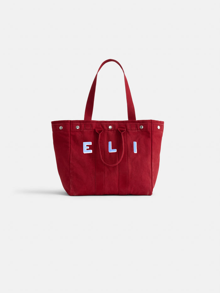 The Perfect Weekday Tote: a red cotton bag with two handles and white and blue "E L I" letters on the front, shown against a plain white background—a stylish monogrammable tote for everyday use.