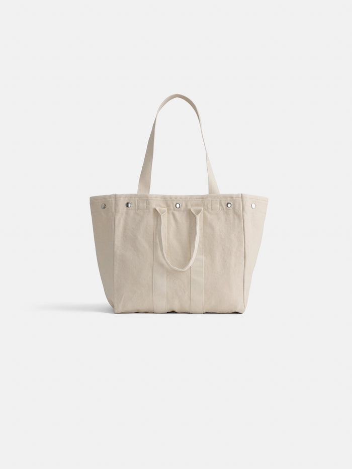 The Perfect Weekday Tote is a beige cotton bag with two short handles, two longer shoulder straps, and metal snap closures on top—ideal for everyday use and shown against a plain white background.