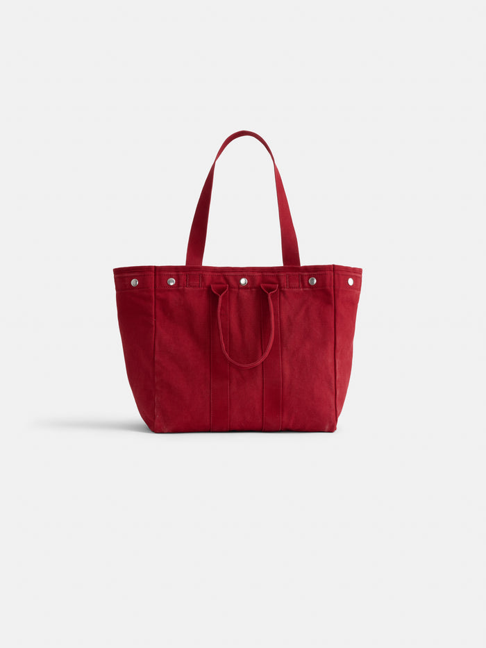 The Perfect Weekday Tote is a large red cotton bag with two shoulder straps, shorter handles, and silver button accents, combining function and style.