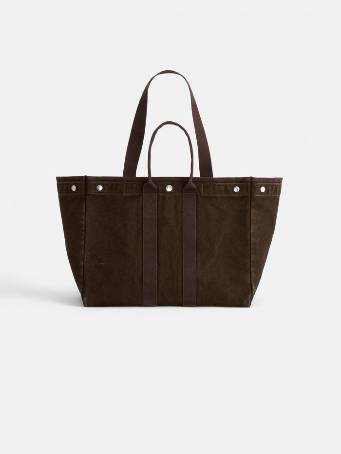The Perfect Weekend Tote is a large, brown cotton bag featuring two short handles and two longer shoulder straps, with silver rivet accents near the top and a boxy, structured design. Displayed against a plain white background, it’s ideal for monogramming or for anyone looking to capture the timeless style associated with an Alex Mill tote.