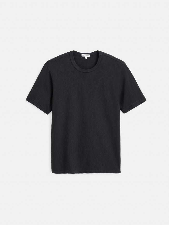The Standard T-Shirt In Slub Cotton—a men’s crew neck tee in plain black with short sleeves, crafted from breathable slub cotton—is laid flat on a white background.