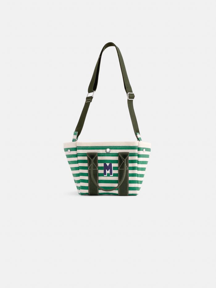 Introducing The Striped Mini: a compact tote bag crafted from green and white striped cotton canvas, featuring dark green handles, an adjustable shoulder strap, and a prominent “M” monogram on the front. This charming accessory is displayed against a simple white background.