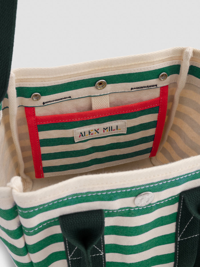 A close-up of the inside of The Striped Mini, a green and cream striped tote with a red-trimmed inner pocket. A label is sewn onto the pocket, ideal for fans of monogrammable bags.