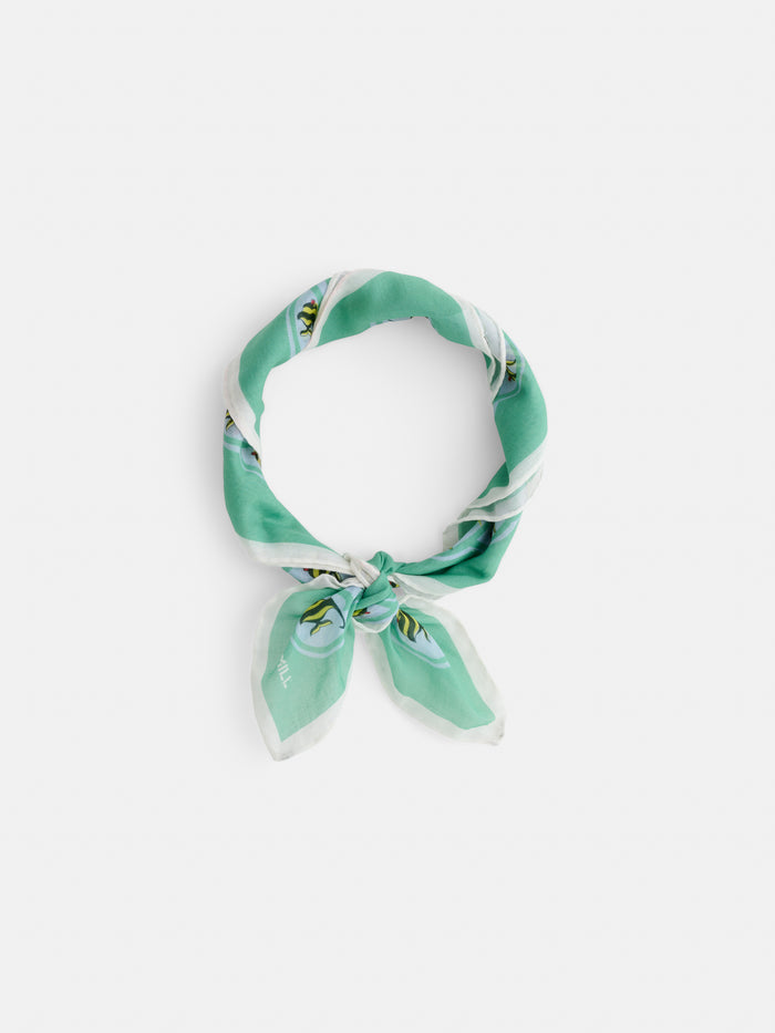 A green and white Travel Scarf in Cotton Voile with a botanical pattern, tied loosely on a white background, channels vintage bandana style and draws inspiration from iconic Hawaii landmarks.