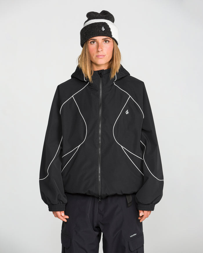 A person wearing the Volcom Unisex Liftline 20K Jacket—featuring a baggy fit with white piping—paired with black cargo pants and a black and gray beanie, stands facing forward against a plain light background—a stylish choice in women’s snowboarding apparel.