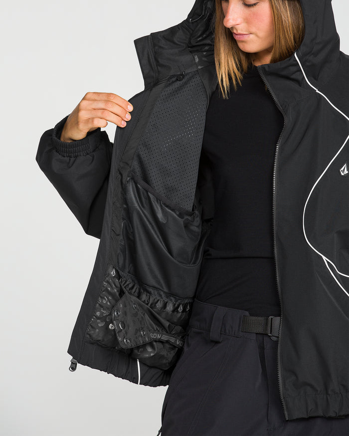 A person in a black, baggy fit Volcom Unisex Liftline 20K Jacket and pants shows the inside of their jacket, revealing multiple mesh and fabric pockets. The snowboarding jacket features a hood, white piping detail, and offers 20K waterproof protection for ultimate performance on the slopes.