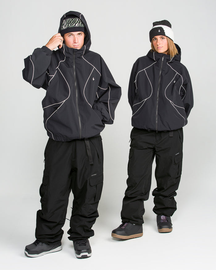 Two people wearing oversized black winter jackets, black snow pants, and beanies stand facing the camera against a plain white background. Both have their hands in their pockets; one adjusts their beanie. Their looks are completed with Volcom’s Unisex Liftline 20K Pants—crafted from recycled fabric—making them perfect for an eco-conscious winter wardrobe.