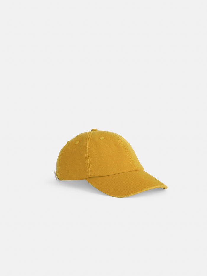 The Washed Canvas Baseball Cap in mustard yellow cotton features a curved brim and an adjustable back strap, shown on a plain white background.