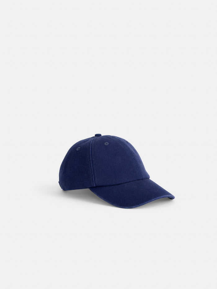 The Washed Canvas Baseball Cap, crafted from durable navy blue cotton canvas with visible stitching, is shown against a plain white background.