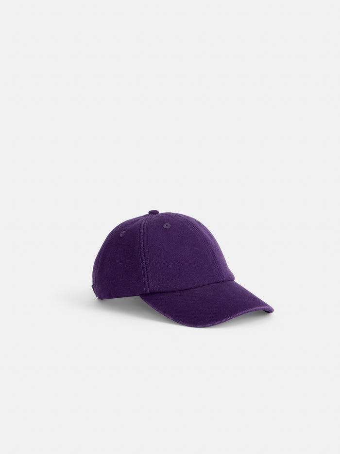 The Washed Canvas Baseball Cap is a plain purple cotton hat with a curved brim, shown on a light gray background. This adjustable cap offers comfort and style, making it perfect for any casual outfit.