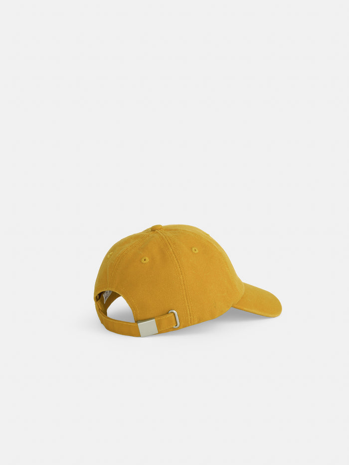 The Washed Canvas Baseball Cap in mustard yellow cotton canvas is shown from the back with an adjustable strap and metal buckle, set against a plain white background.
