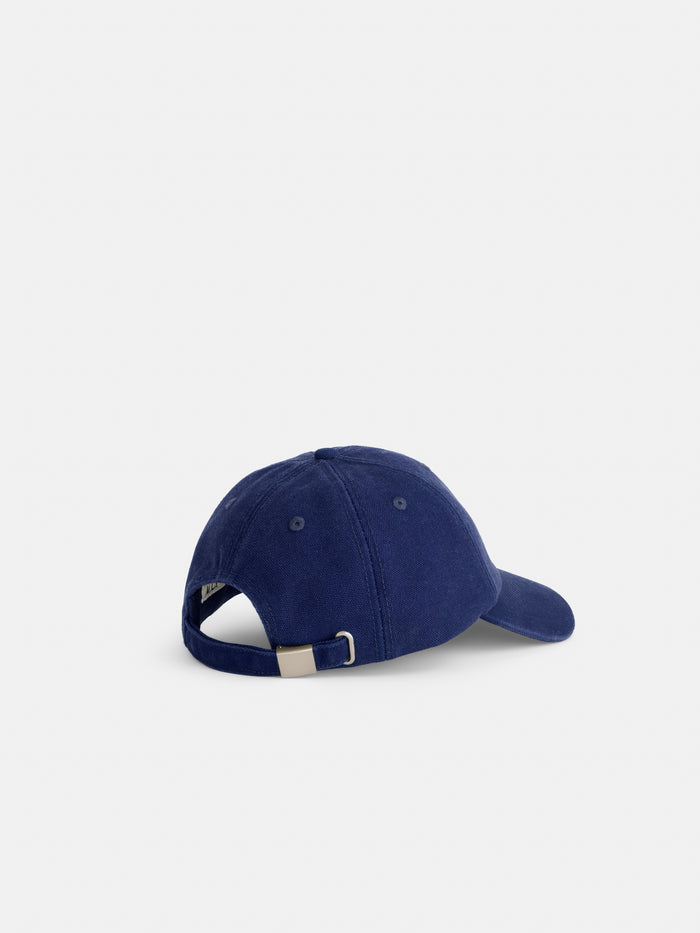 The Washed Canvas Baseball Cap in navy blue cotton canvas is shown from the back, highlighting its adjustable strap with metal buckle. Set against a plain white background.