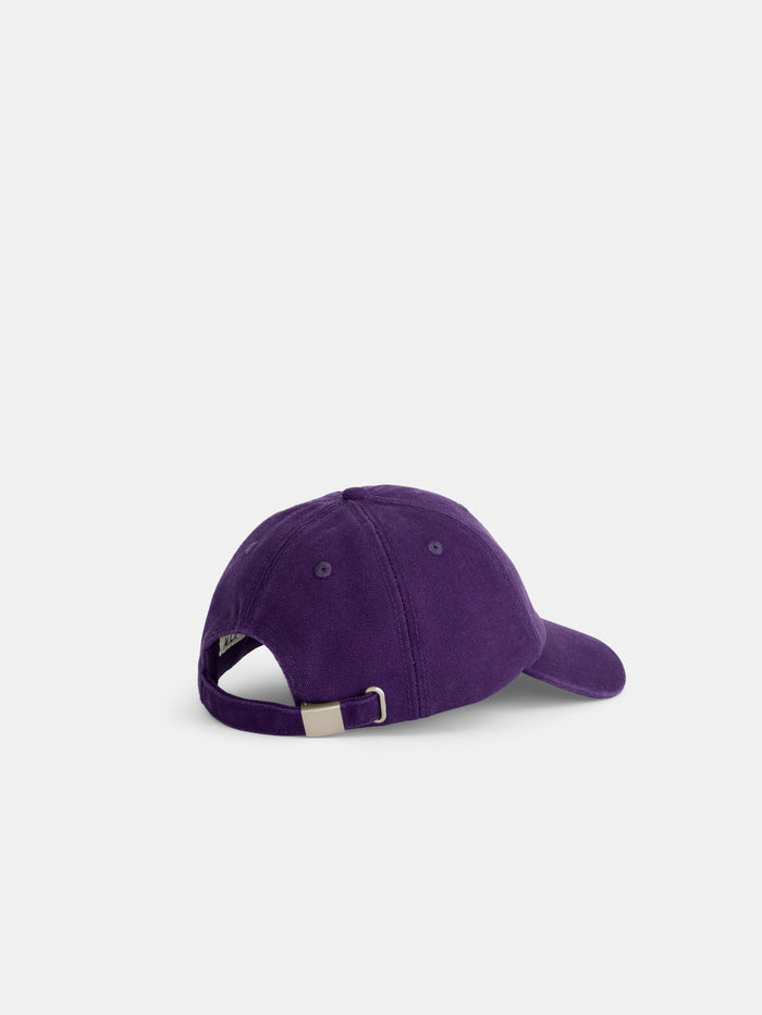 The Washed Canvas Baseball Cap, made of purple cotton canvas, is shown from the back with an adjustable strap and metal buckle, set against a plain white background.