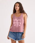 A woman stands against a plain white background wearing the Volcom Women's Amakua Bank Tank, a mauve knit tank top featuring Hawaii-inspired Volcom and floral graphics, paired with denim shorts.