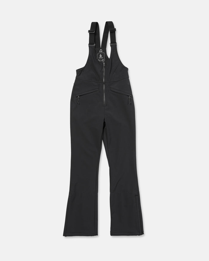 The Volcom Women’s Battle Stretch Bib snow pants feature a black stretch bib-style design with adjustable shoulder straps, a front zipper, zippered side pockets, and flared legs. They are PFAS-free DWR coated for eco-friendly water resistance and offer 15K/10K protection. The pants are shown laid flat on a white background.