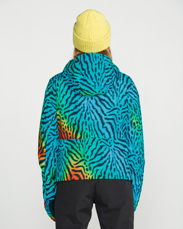 Wearing the Volcom Women’s Bolt Insulated Jacket featuring vibrant blue, green, and orange zebra stripes, and a yellow knit beanie, a person stands facing away against a plain white background.