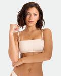 A woman with short, wavy brown hair models the Volcom Women's Coco Low Tide Bandeau Bra in light beige textured fabric, holding one removable adjustable strap and looking confidently at the camera against a plain light background.