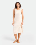 A woman stands barefoot against a plain background, wearing the Volcom Women's Coco Low Tide Midi Dress—a cream, sleeveless, body-con tank dress with vertical eyelet patterns, side slit, and knee-length cut.