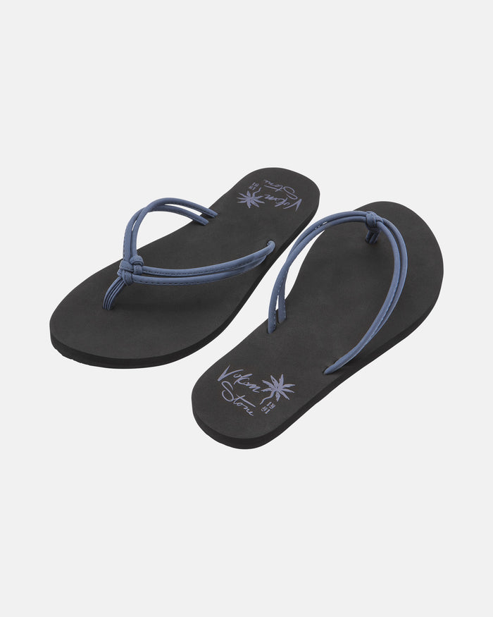 The Volcom Women's Forever And Ever II flip-flops feature black soles with thin blue straps and decorative writing plus palm tree graphics on the insoles, shown against a plain white background.