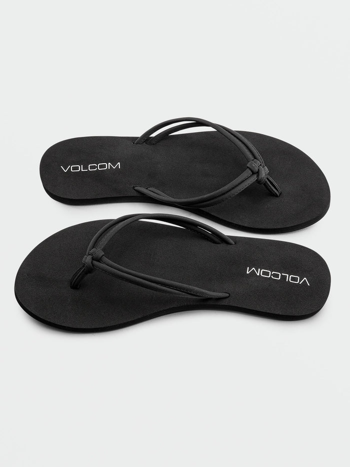 A pair of Volcom Women's Forever And Ever II black flip-flops, featuring thin synthetic leather straps and "VOLCOM" printed in white on the footbeds, with molded arch support for added comfort, displayed on a white background.