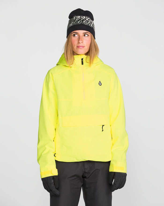 Wearing the Volcom Women’s Harlan Pullover in yellow, paired with black pants, gloves, and a black beanie, a person stands facing forward against a plain light background.