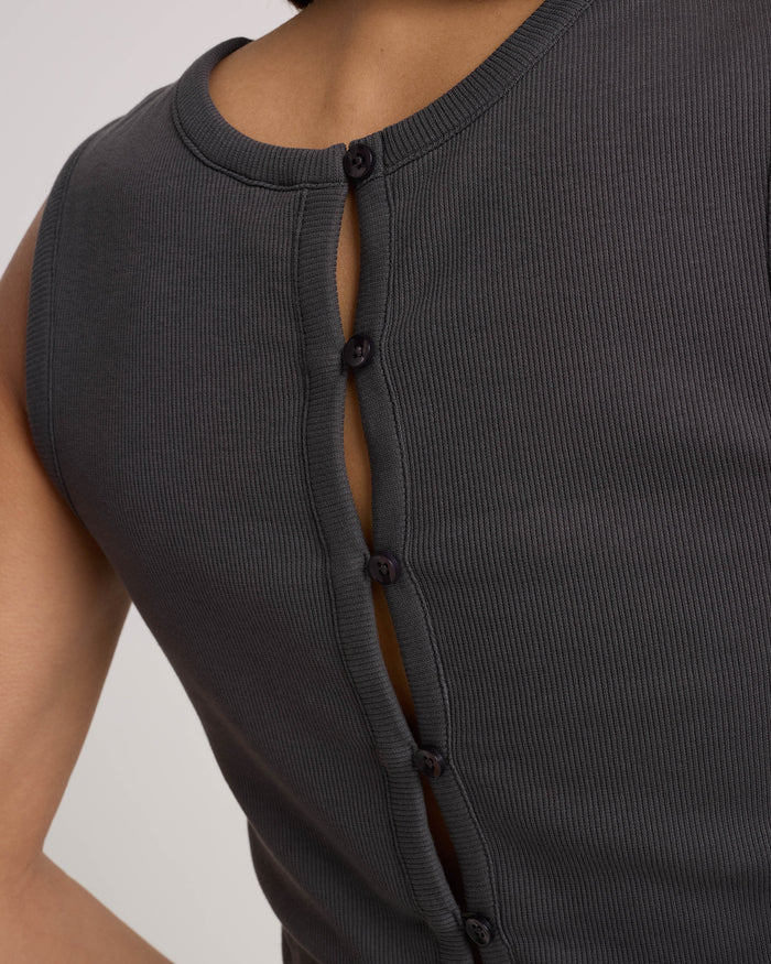 A close-up of a person's back wearing the Women's Mary Mack Tank by Volcom, a fitted crew-neck style crafted from a vintage black cotton blend with a sleeveless, ribbed design and a vertical row of buttons down the back.