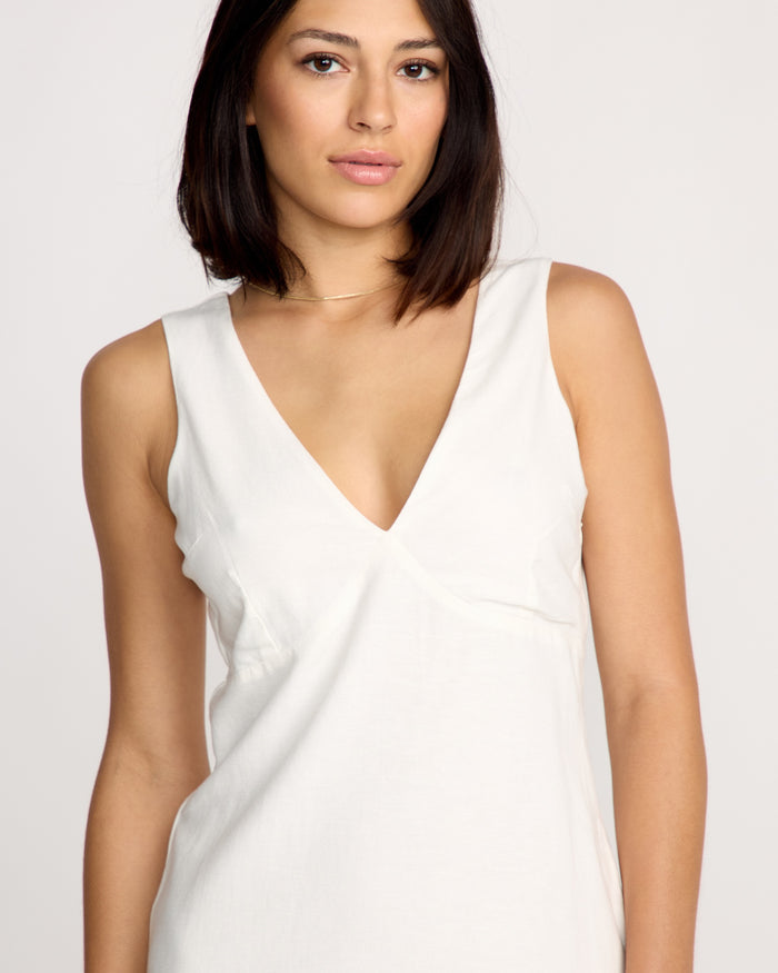 A woman with straight dark hair and medium skin tone wears the sleeveless white Volcom Women's Money Mama Dress and a thin necklace, standing against a plain light background.