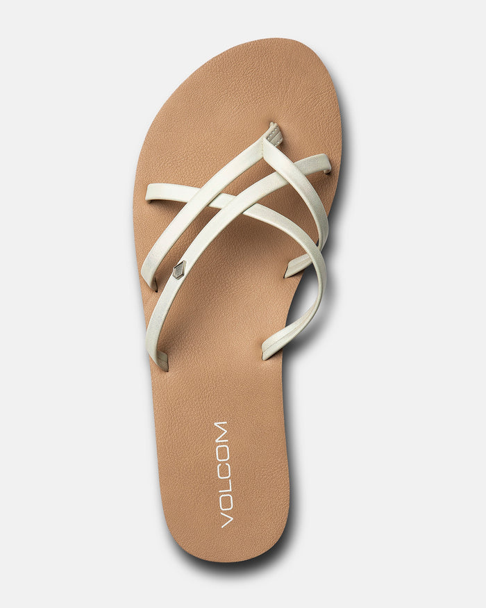 The Volcom Women's New School II sandal features thin cream synthetic leather straps, molded arch support, and "VOLCOM" printed near the heel on the footbed, shown as a single tan sandal against a white background.