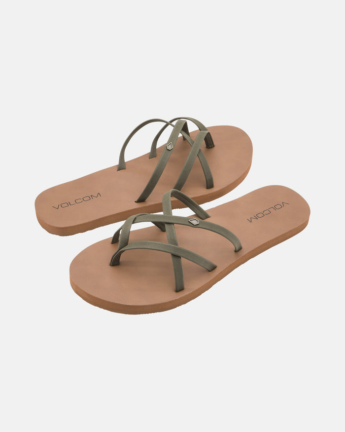 The Volcom Women's New School II features brown flat sandals with olive green synthetic leather crisscross straps, Recliner Comfort Foam, and the Volcom logo on the footbed, shown against a white background.