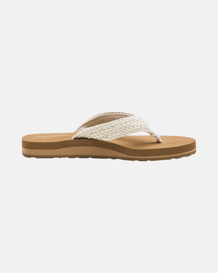 The Volcom Women's Oasis Sandals feature a tan flip-flop design with a textured, woven white strap and brown cushioned sole, shown in side view on a plain white background.