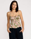 A woman with straight dark hair wears the Volcom Women's Psychonic Cami with adjustable straps and black pants, standing with her hands in her pockets against a plain light background.