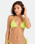 A woman with shoulder-length brown hair and a small butterfly tattoo on her left ribcage poses against a light background, touching her hair while wearing the Volcom Women's Pucker Up Triangle Top in bright Acid Lemon, crafted from recycled fabric.