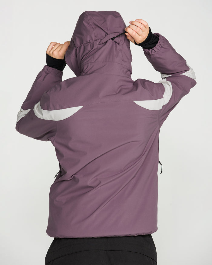 A person wearing the Volcom Women’s Shelter 3D Stretch Jacket in purple, featuring waterproof insulation and reflective stripes, is seen from behind adjusting the hood with both hands against a plain, light-colored background.