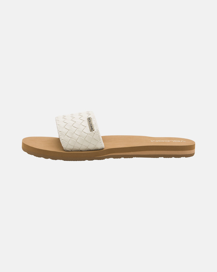 The Volcom Women's Simple Slides Braid Sandals feature a white woven strap and tan flat sole, shown in side profile view against a white background.