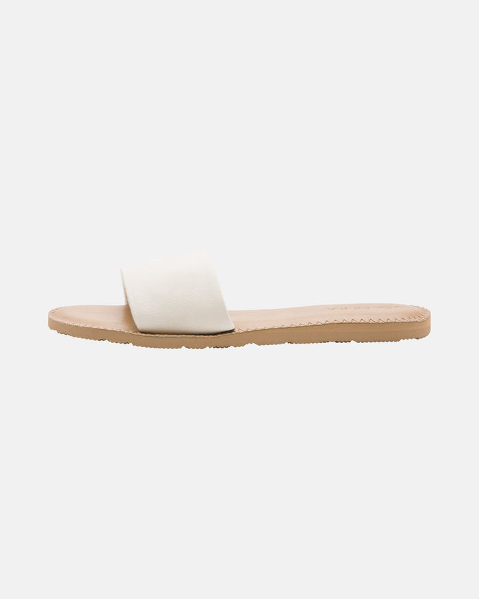 The Volcom Women's Simple Slide is a minimalist flat sandal with a tan sole and a wide white strap, shown in side profile on a plain white background.